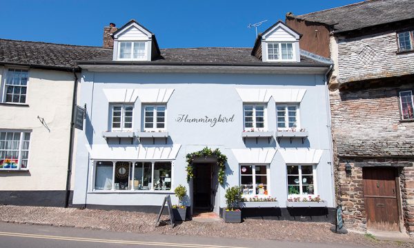 gery three storied historic property with a central door between the shop windows